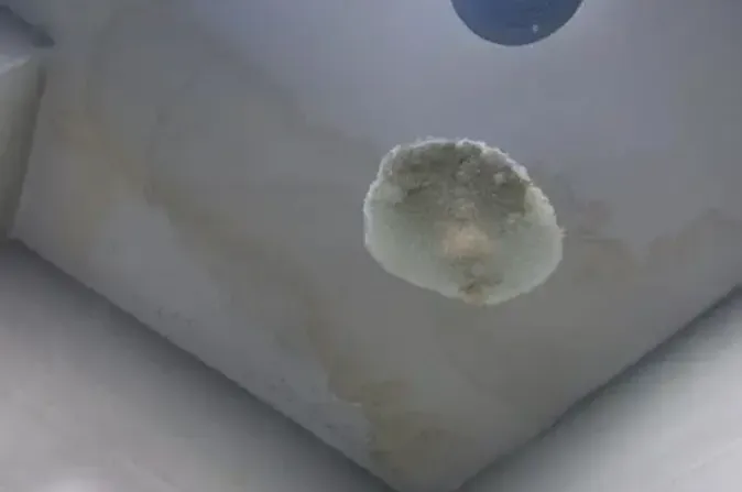Water stained ceiling with a rounded bulge where water has collected behind the paint